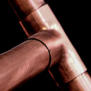 Ends of copper pipes against a dark background